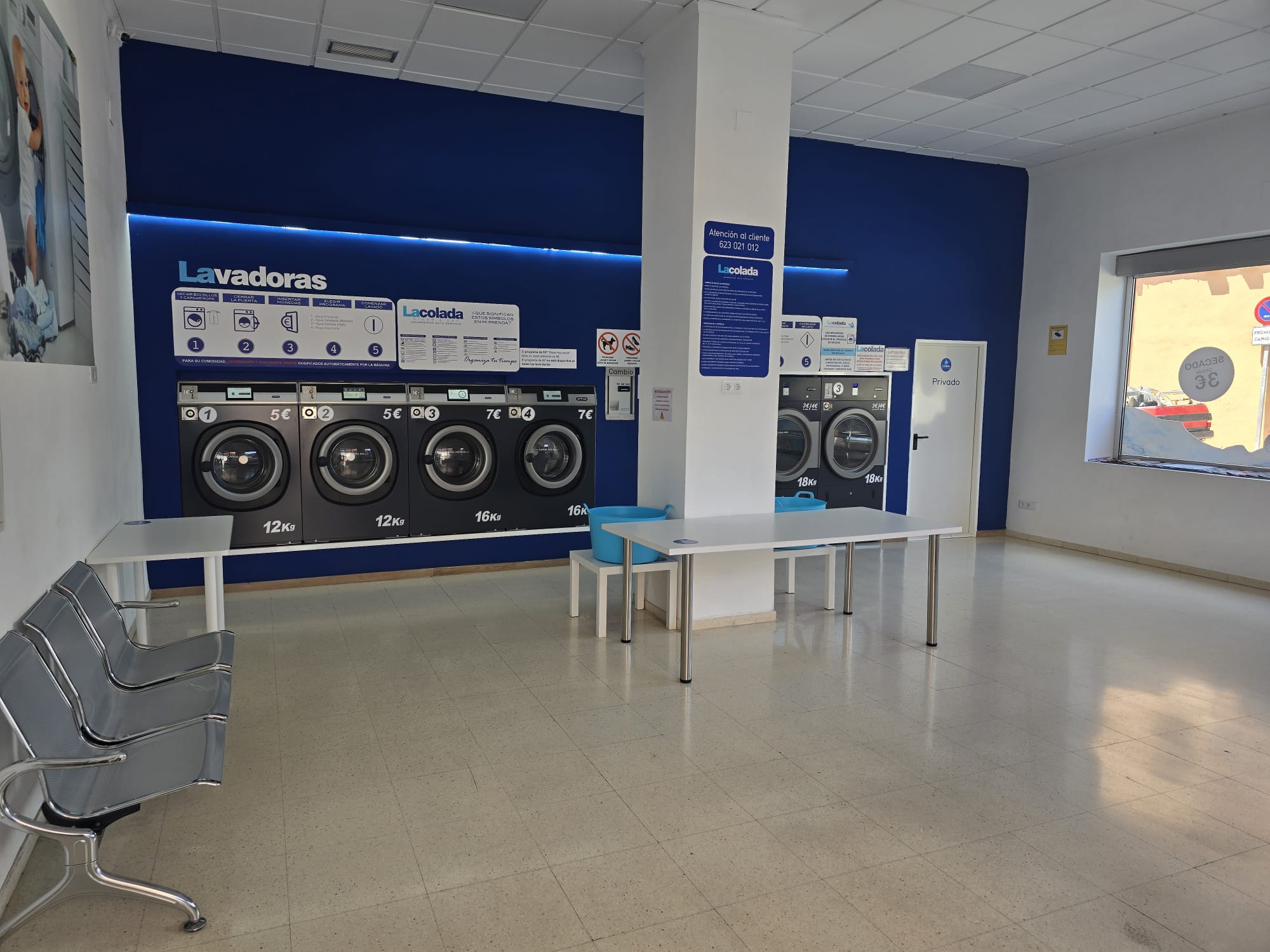 Interior de una lavandería autoservicio luminosa con una fila de lavadoras